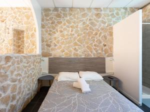 a bedroom with a bed and a stone wall at Hotel De Belgique à Menton in Menton