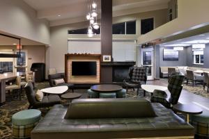 un vestíbulo con mesas, sillas y chimenea en Residence Inn by Marriott Springfield South, en Springfield