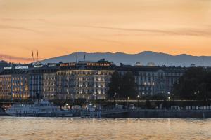 ein großes Gebäude am Ufer eines Wasserkörpers in der Unterkunft The Ritz-Carlton Hotel de la Paix, Geneva in Genf