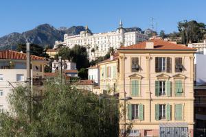 a large yellow building in front of a mountain at Hotel De Belgique à Menton in Menton
