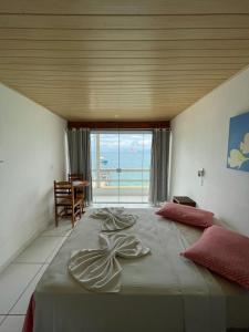 a bedroom with a large bed with a view of the ocean at Pousada do Preto in Praia do Bananal