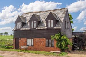 a house with a gambrel roof on top of it at Stylish rural cottage with views over fields and the River Stour - The Granary in Colchester