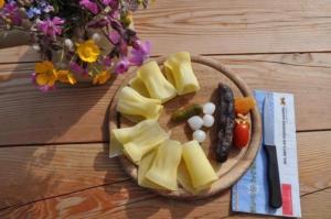 un plato de comida con queso y verduras en una mesa en Zimmer in uriger rustikalen Alphütte auf bewirtschafteter Alp hoch in den Bergen, inkl VP en Leukerbad