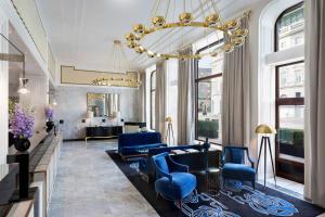 a living room with blue chairs and a chandelier at Hotel Bristol, A Luxury Collection Hotel, Warsaw in Warsaw
