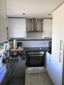 a kitchen with stainless steel appliances and white cabinets at Private Garden Lodge in Christchurch, Dorset for 4 - dogs welcome! in Holdenhurst