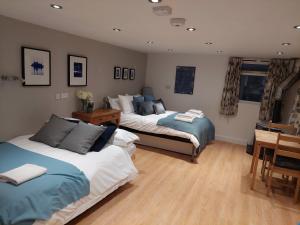 a bedroom with two beds and a table and a desk at Private Garden Lodge in Christchurch, Dorset for 4 - dogs welcome! in Holdenhurst