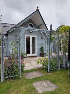 une petite maison bleue avec un portail en face de celle-ci dans l'établissement Private Garden Lodge in Christchurch, Dorset for 4 - dogs welcome!, à Holdenhurst
