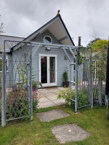 a small blue house with a gate in front of it at Private Garden Lodge in Christchurch, Dorset for 4 - dogs welcome! in Holdenhurst