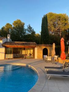 a swimming pool with umbrellas next to a house at Une Pause en Provence in Le Beausset