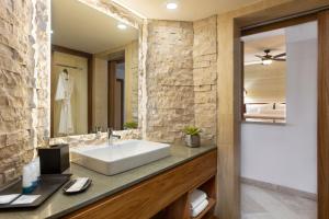 a bathroom with a white sink and a stone wall at The Westin Reserva Conchal, an All-Inclusive Golf Resort & Spa in Playa Conchal