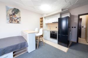 a small room with a bed and a black refrigerator at Luxury Studio Apartment - Varna Residens in Varna City
