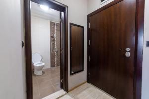 a bathroom with a toilet and a wooden door at Luxury Studio Apartment - Varna Residens in Varna City