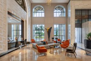 a lobby with a couch and chairs and windows at Le Royal Méridien Doha in Doha