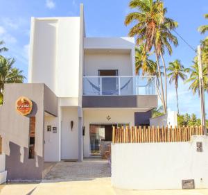 a white house with palm trees in the background at Casa Mar do Patacho in Pôrto de Pedras