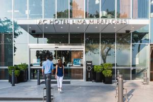 a man and woman walking in front of a building at AC Hotel by Marriott Lima Miraflores in Lima