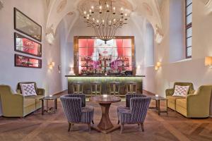 プラハにあるオーガスティン ア ラグジュアリー コレクション ホテル プラハの椅子とテーブル、シャンデリアのあるバー