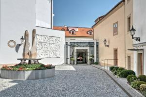einen Innenhof mit einer Statue vor einem Gebäude in der Unterkunft Augustine, a Luxury Collection Hotel, Prague in Prag