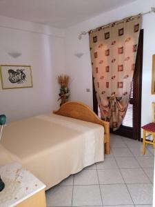 a bedroom with a bed and a window with a curtain at Le Canne Apt 1 in San Teodoro