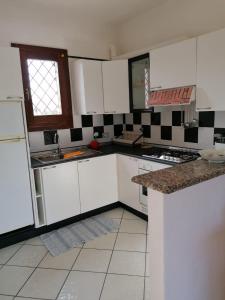 a kitchen with white cabinets and a sink and a window at Le Canne Apt 1 in San Teodoro