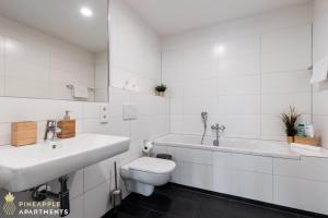 La salle de bains blanche est pourvue de toilettes, d'un lavabo et d'une baignoire. dans l'établissement Pineapple Apartments Dresden Altstadt III - 91 qm - 1x free parking, à Dresde