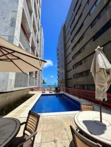 - une piscine avec une table et un parasol dans l'établissement HOTEL NAVEGANTES VISTA PARA MAR Boa Viagem, à Récife