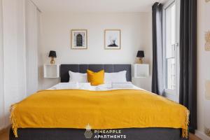 a bedroom with a large bed with a yellow blanket at Pineapple Apartments Dresden Altstadt V - 112 qm - 1x free parking in Dresden
