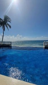 a large swimming pool next to the ocean with a palm tree at Hotel Casa Canada in Big Corn Island