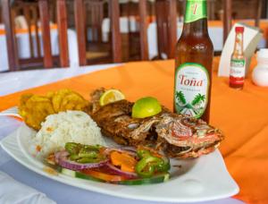 a plate of food with rice and a bottle of beer at Hotel Casa Canada in Big Corn Island