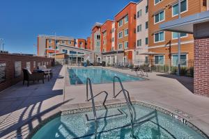 una piscina con sillas, mesas y edificios en Residence Inn Sacramento Davis, en Davis