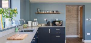 a kitchen with a sink and a blue wall at Green End Farm Cottages - The Cow Barn in Goathland