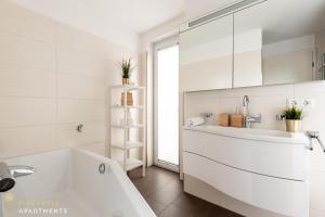 La salle de bains blanche est pourvue d'une baignoire et d'un lavabo. dans l'établissement Pineapple Apartments Dresden Zwinger III - 86 qm - 1x free parking, à Dresde