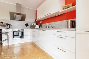 eine Küche mit weißen Schränken und einer orangefarbenen Wand mit Akzenten in der Unterkunft Pineapple Apartments Dresden Zwinger III - 86 qm - 1x free parking in Dresden