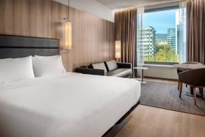 una habitación de hotel con una cama grande y una silla en AC Hotel Diagonal L'Illa by Marriott, en Barcelona