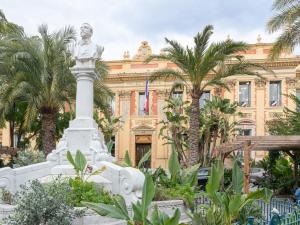 a statue in front of a building with palm trees at Hotel De Belgique à Menton in Menton +37 photos