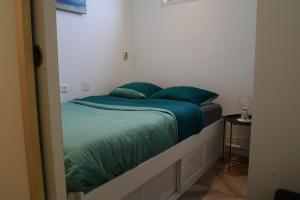 uma cama com lençóis e almofadas verdes num quarto em "Pieds dans l'eau", Dunkerque plage, digue de mer Malo les bains, T2 em Dunkerque