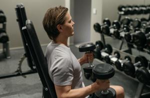 a man sitting in a gym holding weights at Heymo 1 by Sokos Hotels in Espoo