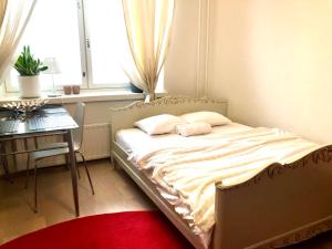 a bedroom with a bed with a table and a window at Sweet home 40 City Center Punavuori in Helsinki