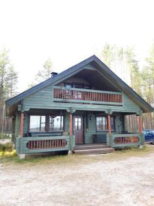 a small green house with a porch and balcony at Vihreä Helmi in Kuusamo