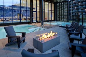 Delta Hotels by Marriott Mont Sainte-Anne, Resort & Convention Center في بوبريه: حوض استحمام ساخن مع كراسي ومدفأة أمامه