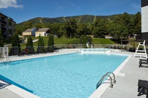 a large swimming pool with chairs and mountains in the background at Delta Hotels by Marriott Mont Sainte-Anne, Resort & Convention Center in Beaupré