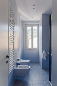 a blue bathroom with a toilet and a window at Olimpico Apartment - Zen Real Estate in Rome