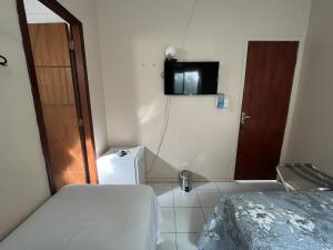 フェルナンド・デ・ノローニャにあるCasa do Anjoのベッド1台、壁掛けテレビが備わる小さな客室です。