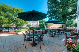 Residence Inn by Marriott Chapel Hill في تشابل هيل: فناء به طاولات وكراسي به مظلات