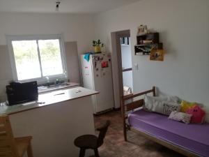 cocina con sofá, mesa y nevera en san vicente en Olavarría