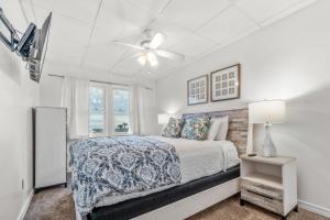een slaapkamer met een bed en een plafondventilator bij The Treehouse On the Bay in Pensacola Beach