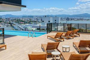 a balcony with chairs and a swimming pool on a building at Studios novos em condomínio com foodhall #TopTower in Florianópolis