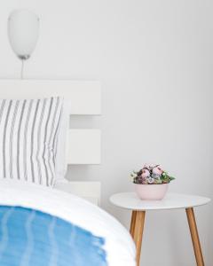 Levendula Apartmanház في باداتشونيتوماي: طاولة عليها وعاء من الزهور بجوار سرير