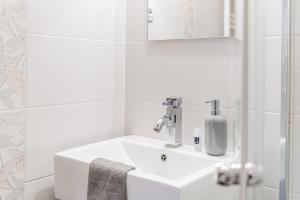 Levendula Apartmanház في باداتشونيتوماي: حمام أبيض مع حوض ومرآة