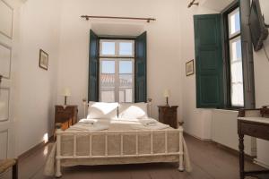 une chambre avec un lit dans une pièce avec des fenêtres dans l'établissement 1861 Mansion Spetses, à Spetses