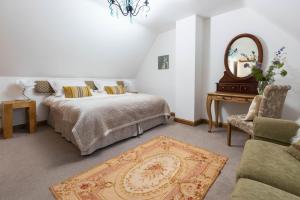 a bedroom with two beds and a mirror and a chair at Little Maunditts Cottage - quiet location in charming Cotswold village in Sherston